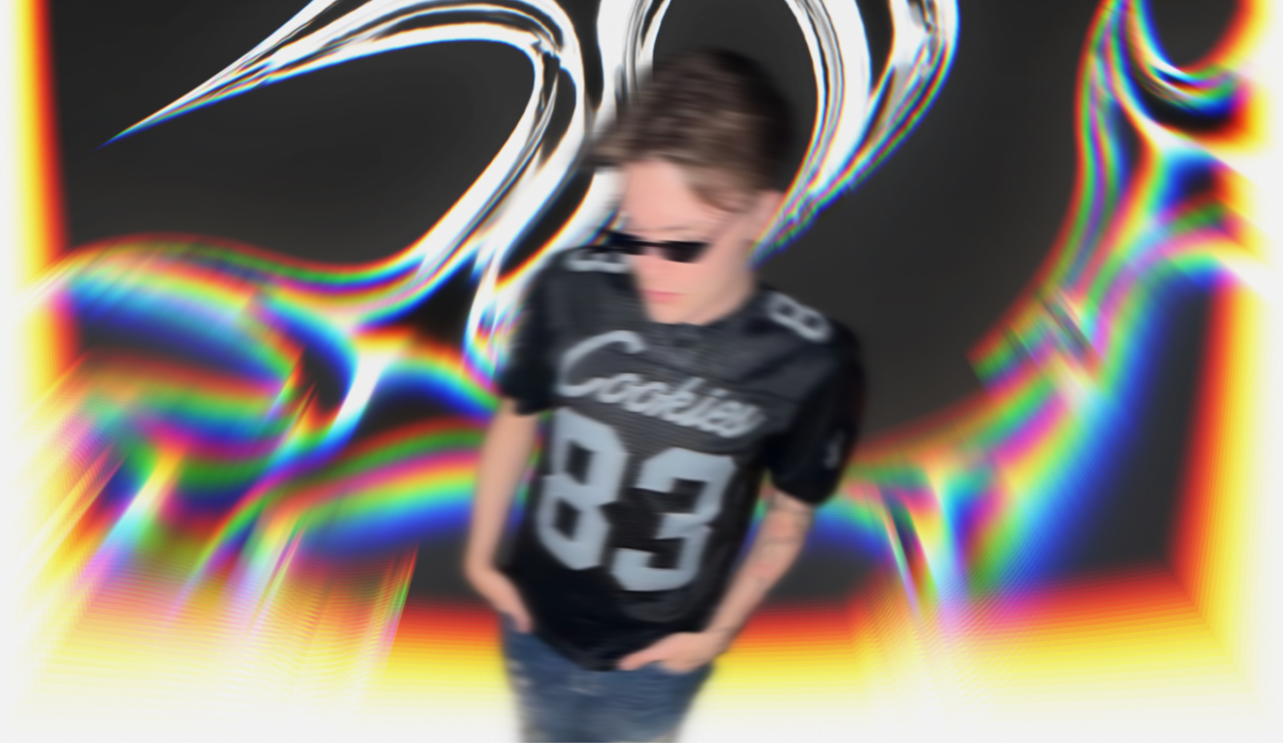Nick sitting on a floor wearing a cool dragon embroidered denim jeans, Spongebob Squarepants shoes, and a black Cookies Jersey